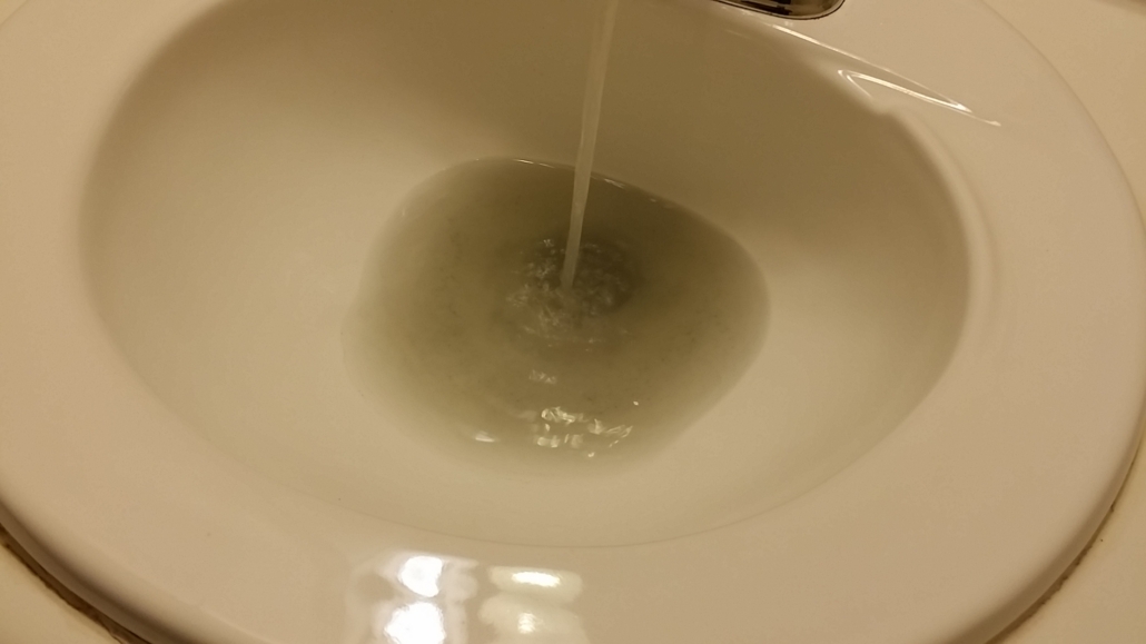 Discolored, contaminated well water running from a faucet before treatment